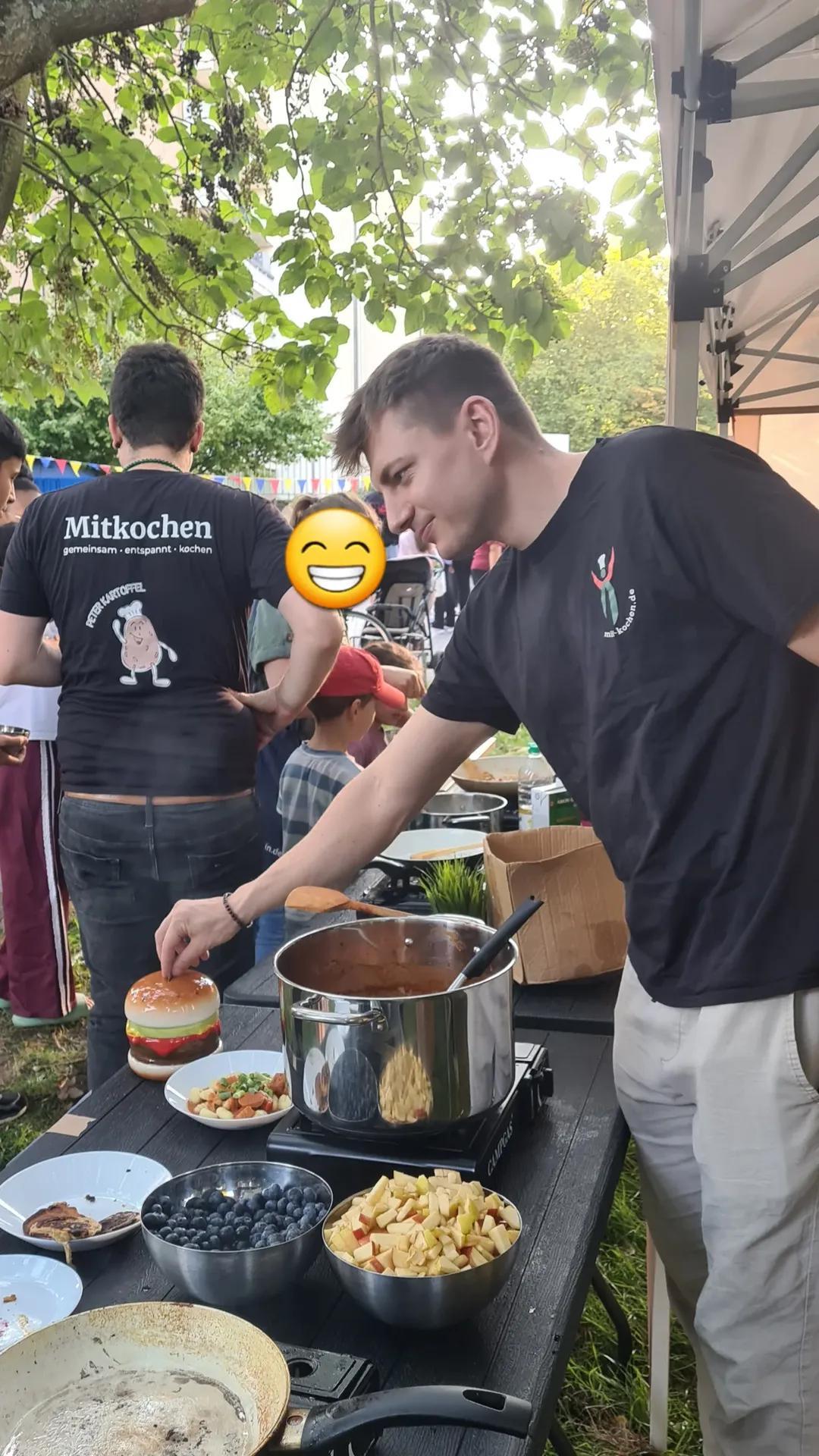 Antonio richtet einen Burger an, während Peter im Hintergrund kocht
