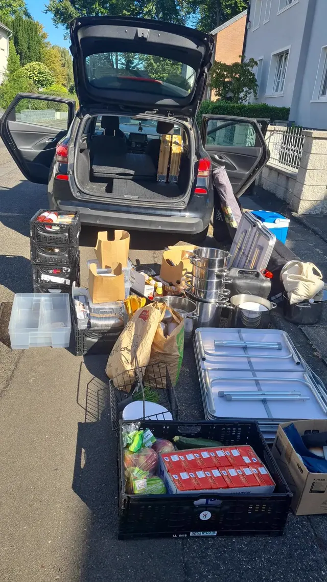 Kofferraum-Küche: das komplette Mitkochen-Equipment vor dem Auto ausgebreitet