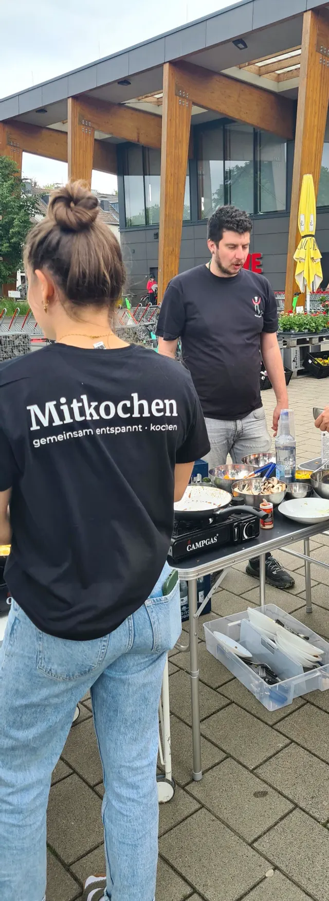 Mitkochen-Shirt von hinten mit Slogan 'gemeinsam entspannt kochen' an der Campgas-Station