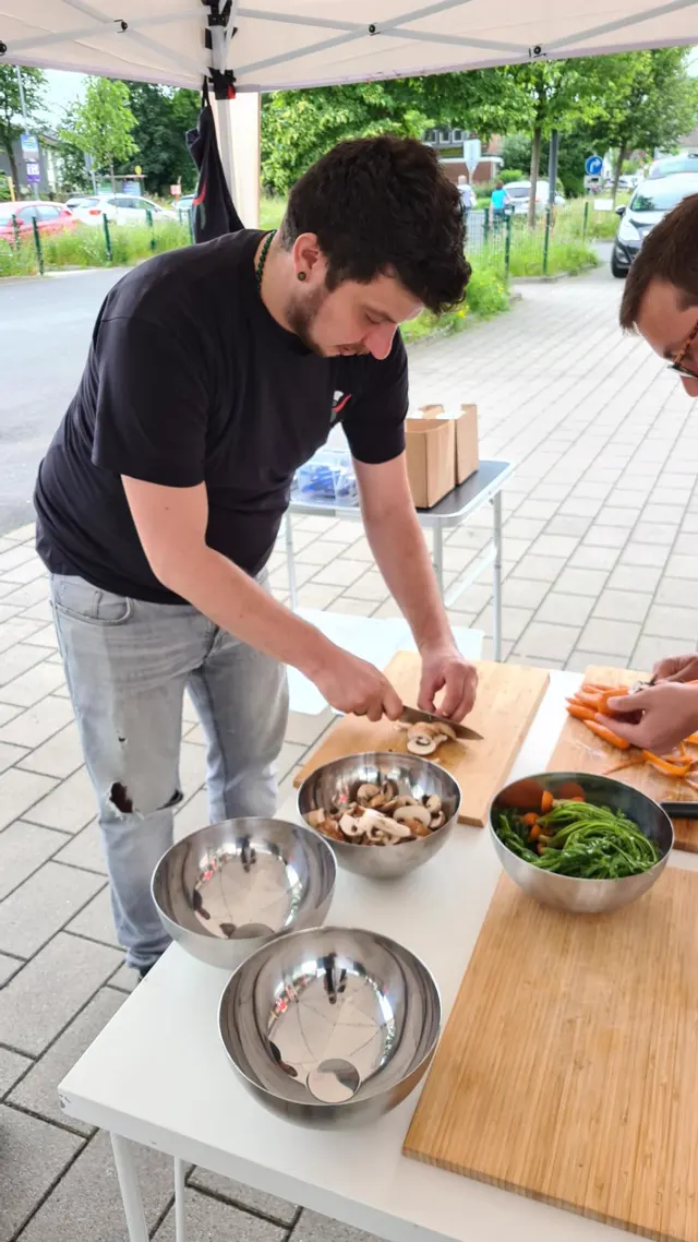 Crew-Mitglied schneidet konzentriert Champignons unterm Pavillon