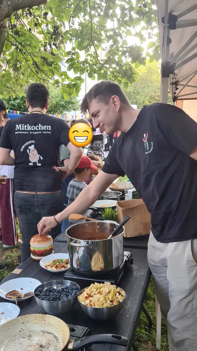 Antonio richtet einen Burger an, während Peter im Hintergrund kocht