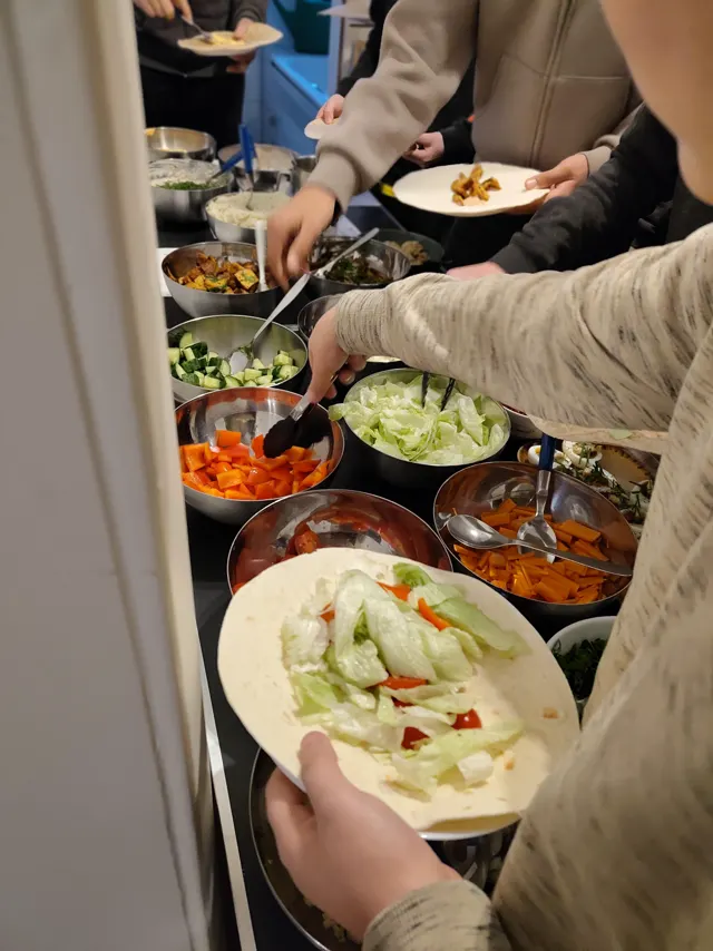 Hände greifen am langen Wrap-Buffet zu Salat, Paprika und Karotten